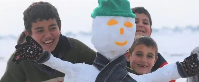 雪だるまと遊ぶ男の子たち